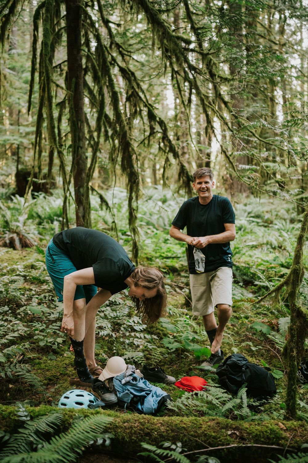 Adventurous couple engagement session photo of couple changing to bike socks in Cumberland Forest Vancouver Island