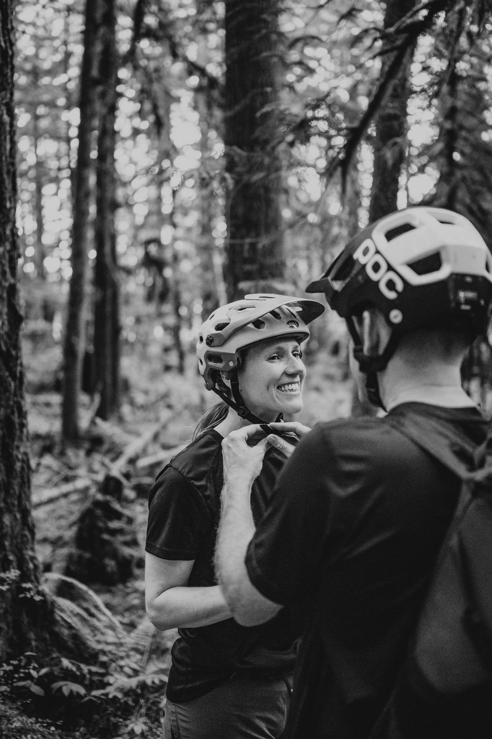 Adventurous couple engagement session photo of couple clipping bike helmets in Cumberland Forest Vancouver Island