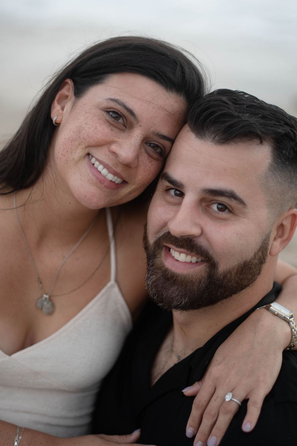 A romantic couple takes close-up selfies together on the beach showing affectionate expressions.