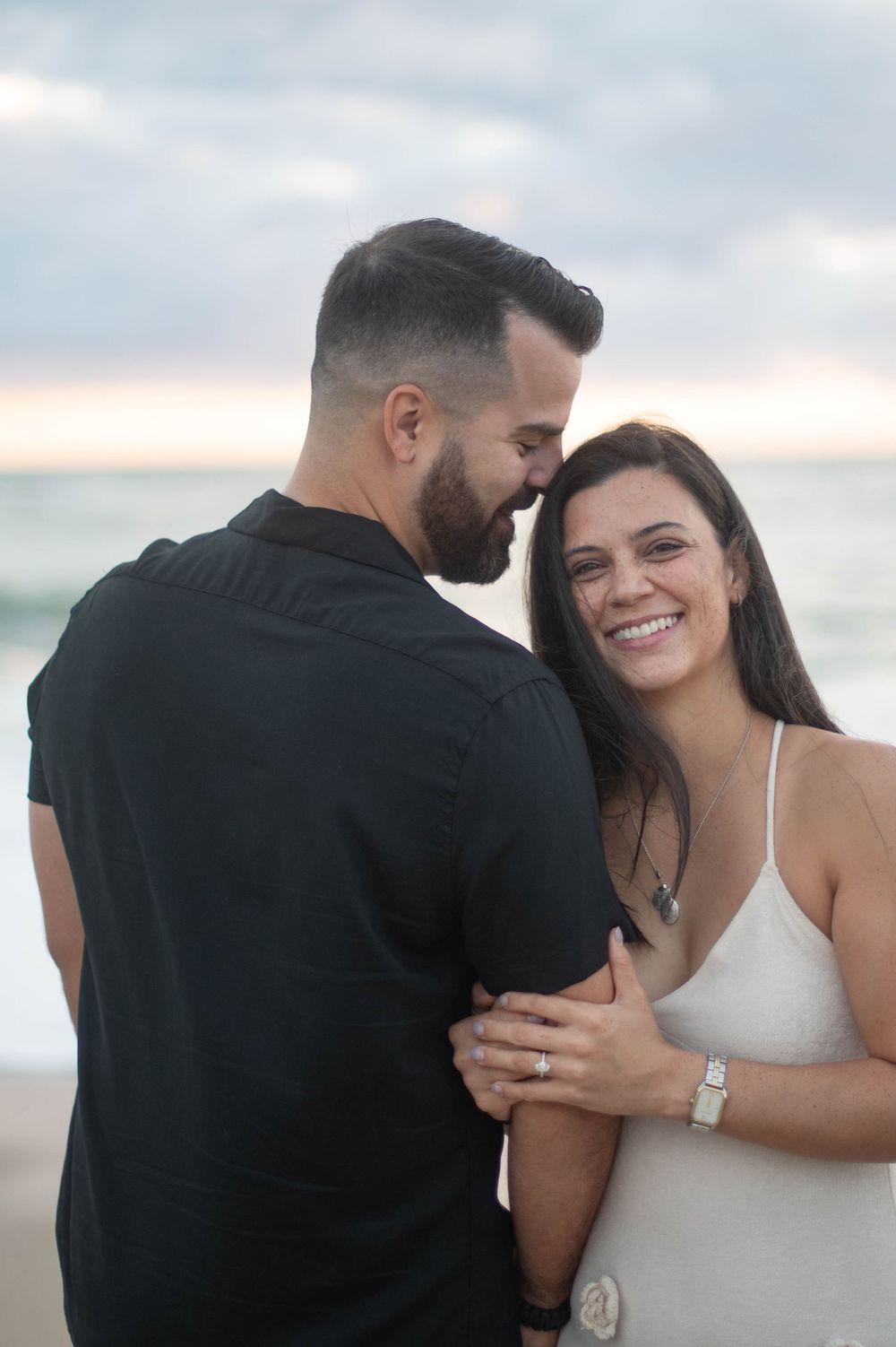 A romantic beach photoshoot sequence showing a couple embracing and laughing together at sunset.