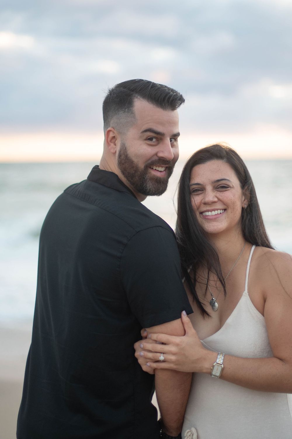 A couple shares joyful moments together during a romantic beachside photoshoot at sunset.