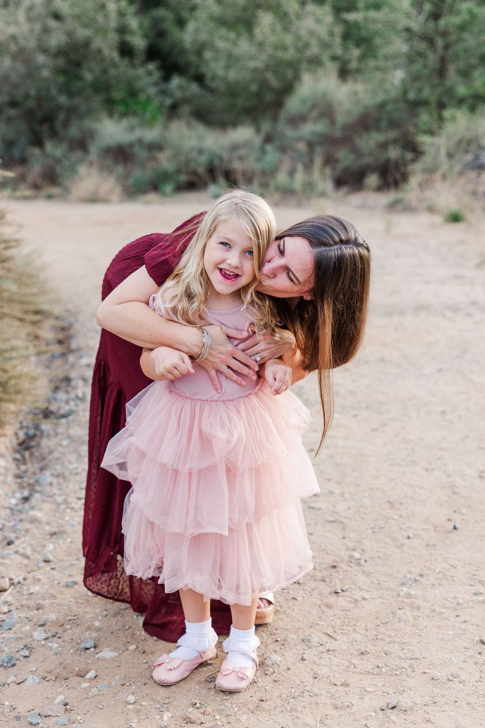 Candid family moments captured on a natural dirt path with mountains in the distance.