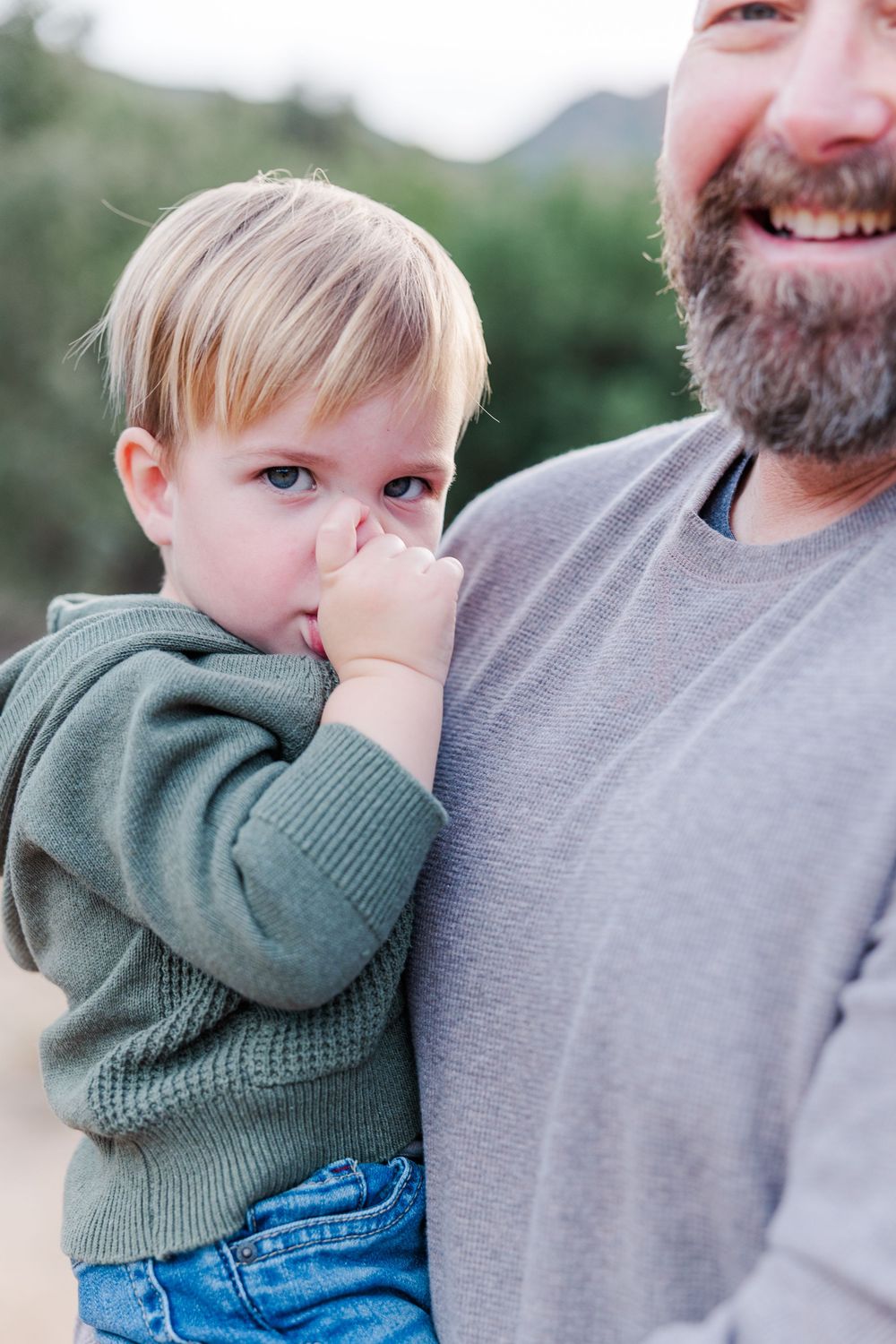 A series of tender moments captured between a small child in a green sweater and an adult in grey.