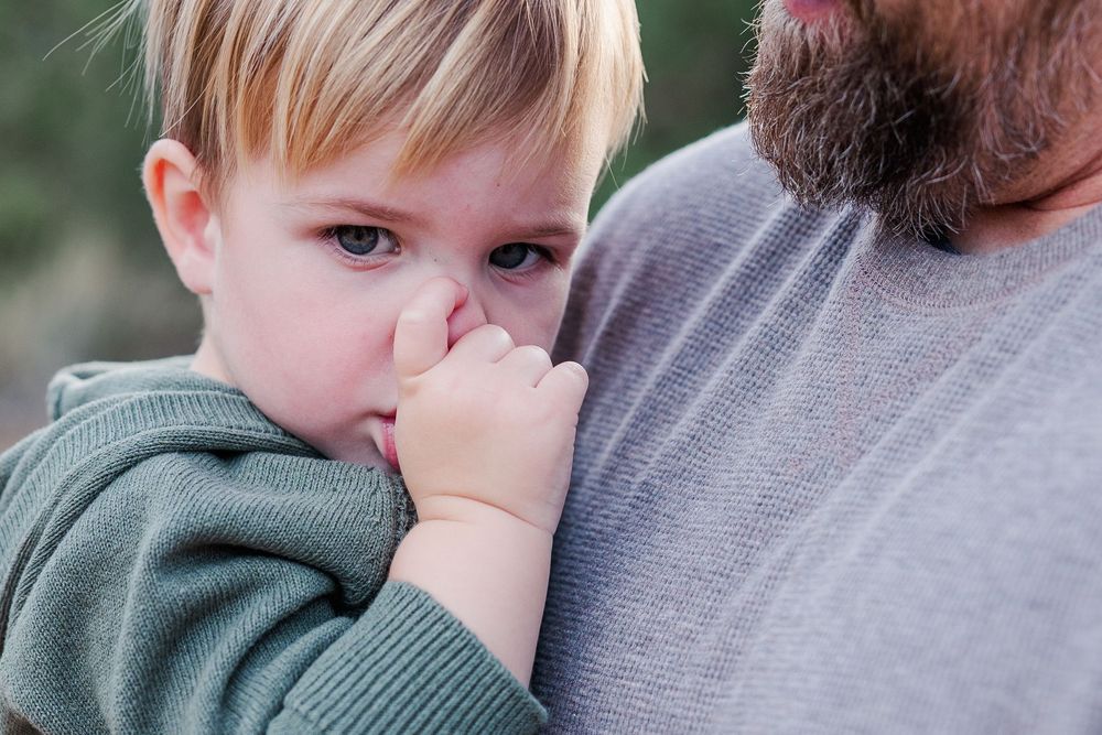 A tender moment between parent and child as they share a close embrace against a soft neutral background.