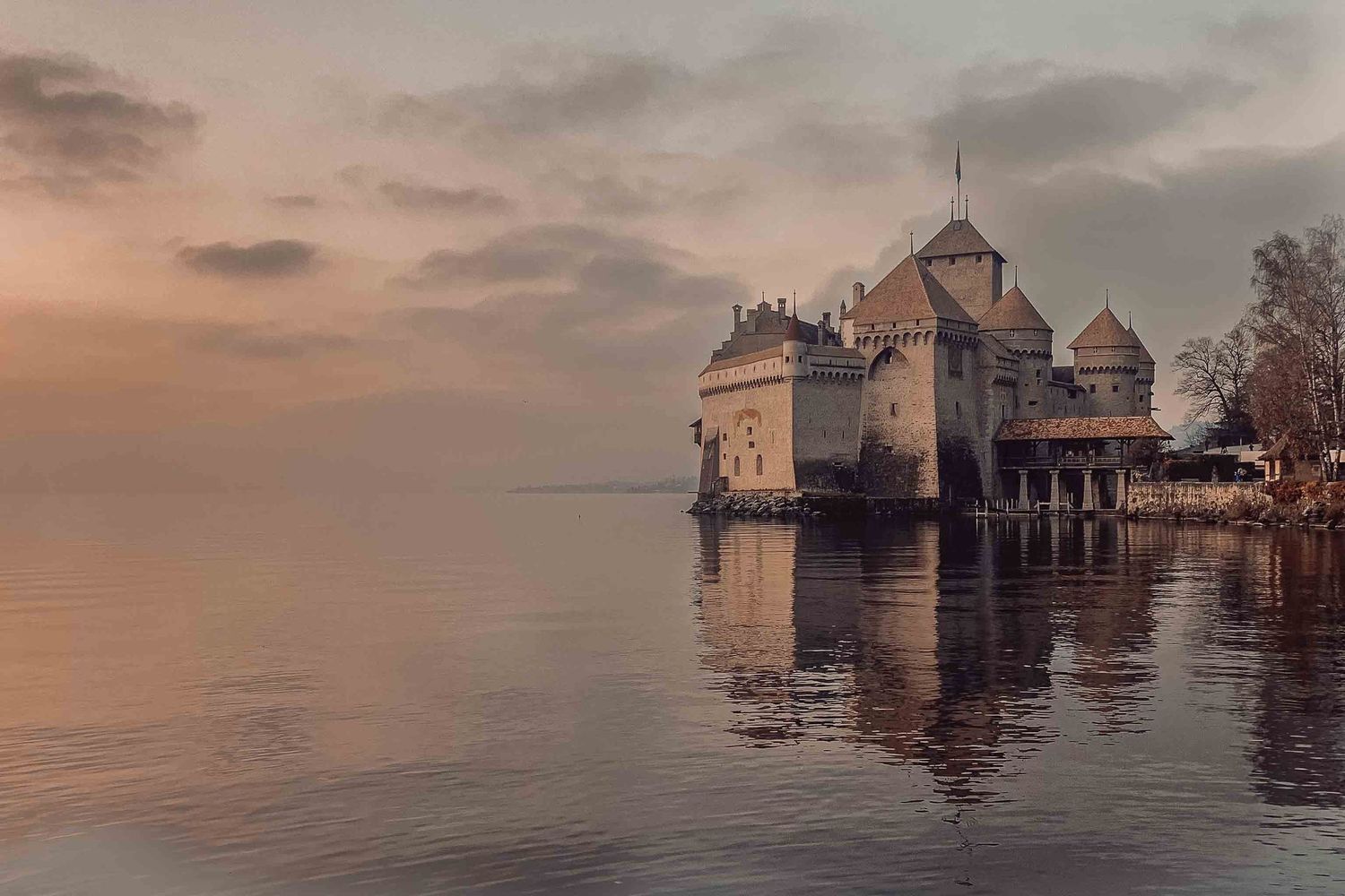 Flooded buildings and structures stand partially submerged in calm waters during sunset creating a haunting reflection.