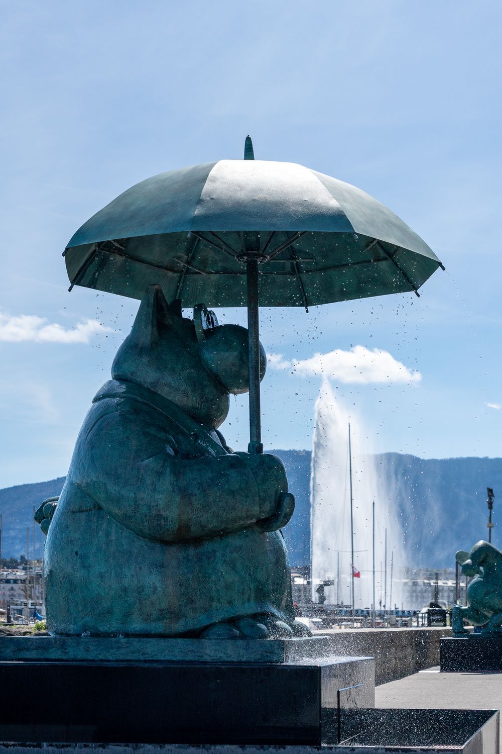 Series of sculptural umbrellas on a waterfront promenade creating an artistic installation against a blue sky.