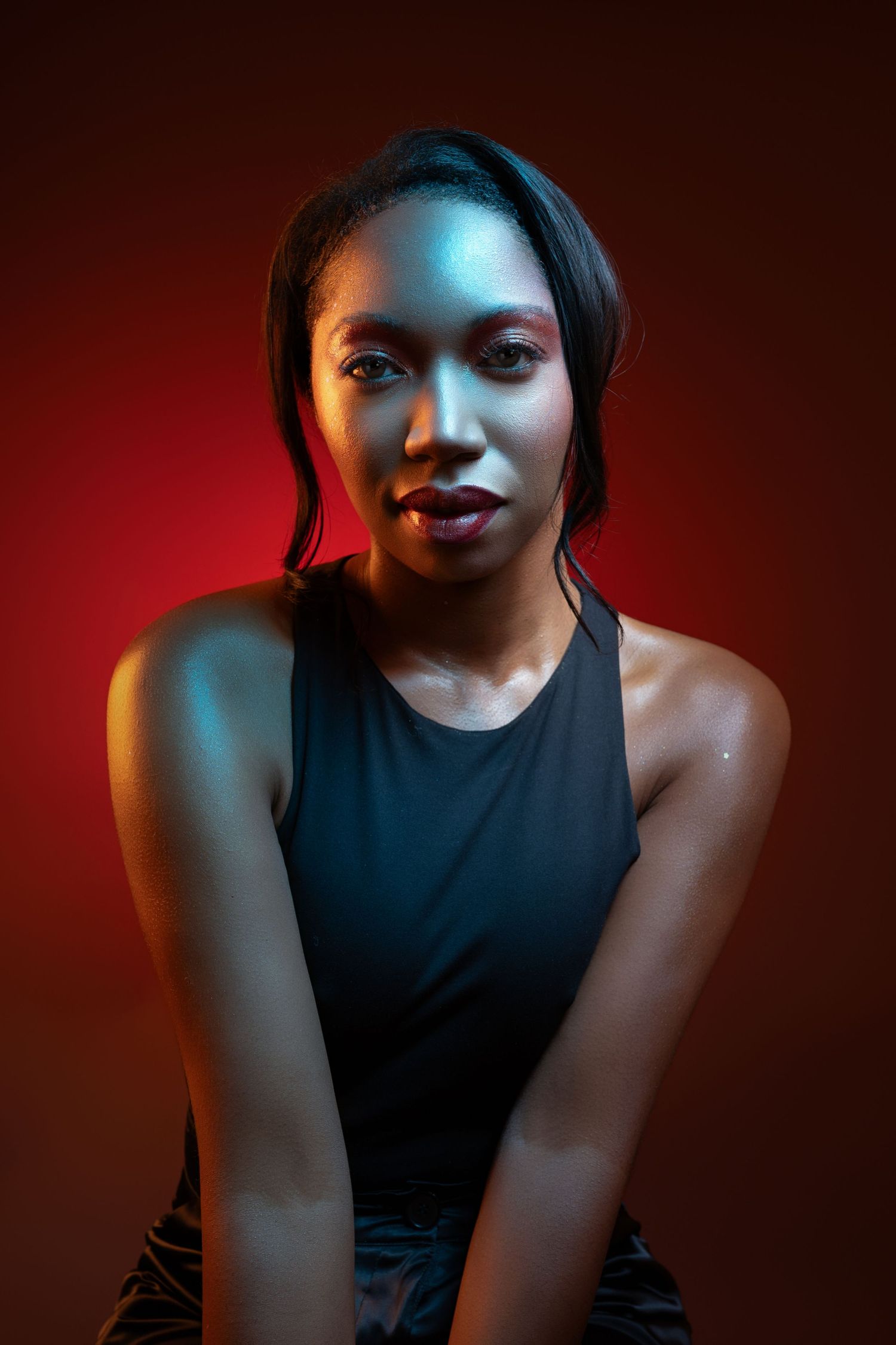 Dramatic portrait series with moody red and blue lighting on a person wearing a black sleeveless top against dark background.
