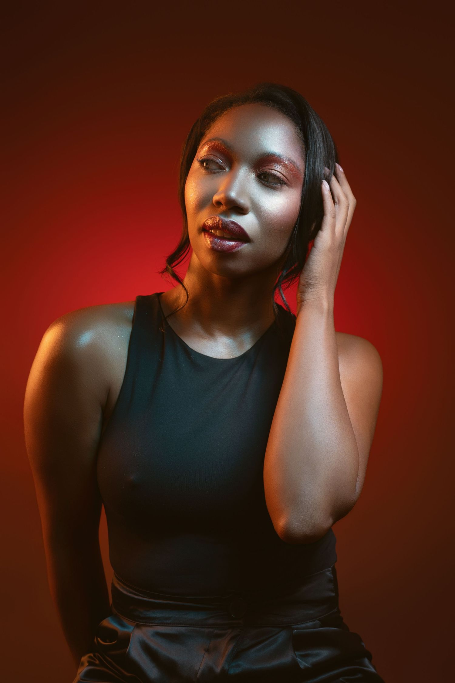 Artistic portrait series in moody red lighting showing figure in black sleeveless top against dark background.