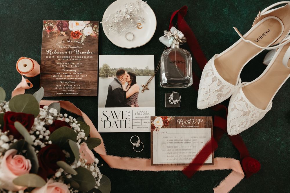 Elegant wedding details including invitations, rings, flowers, and shoes arranged in a romantic flat lay composition.