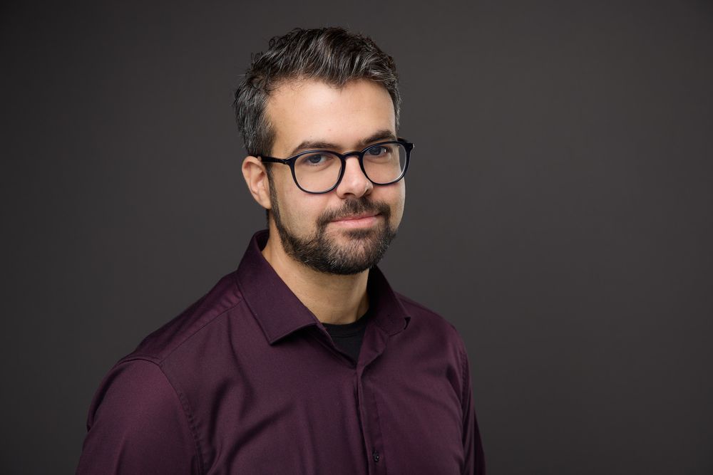 Professional headshot series of a person with glasses and beard wearing a burgundy dress shirt against dark background.