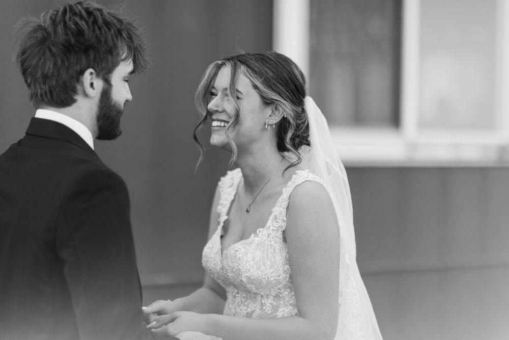 A bride and groom share a joyful moment together during their black and white wedding ceremony.