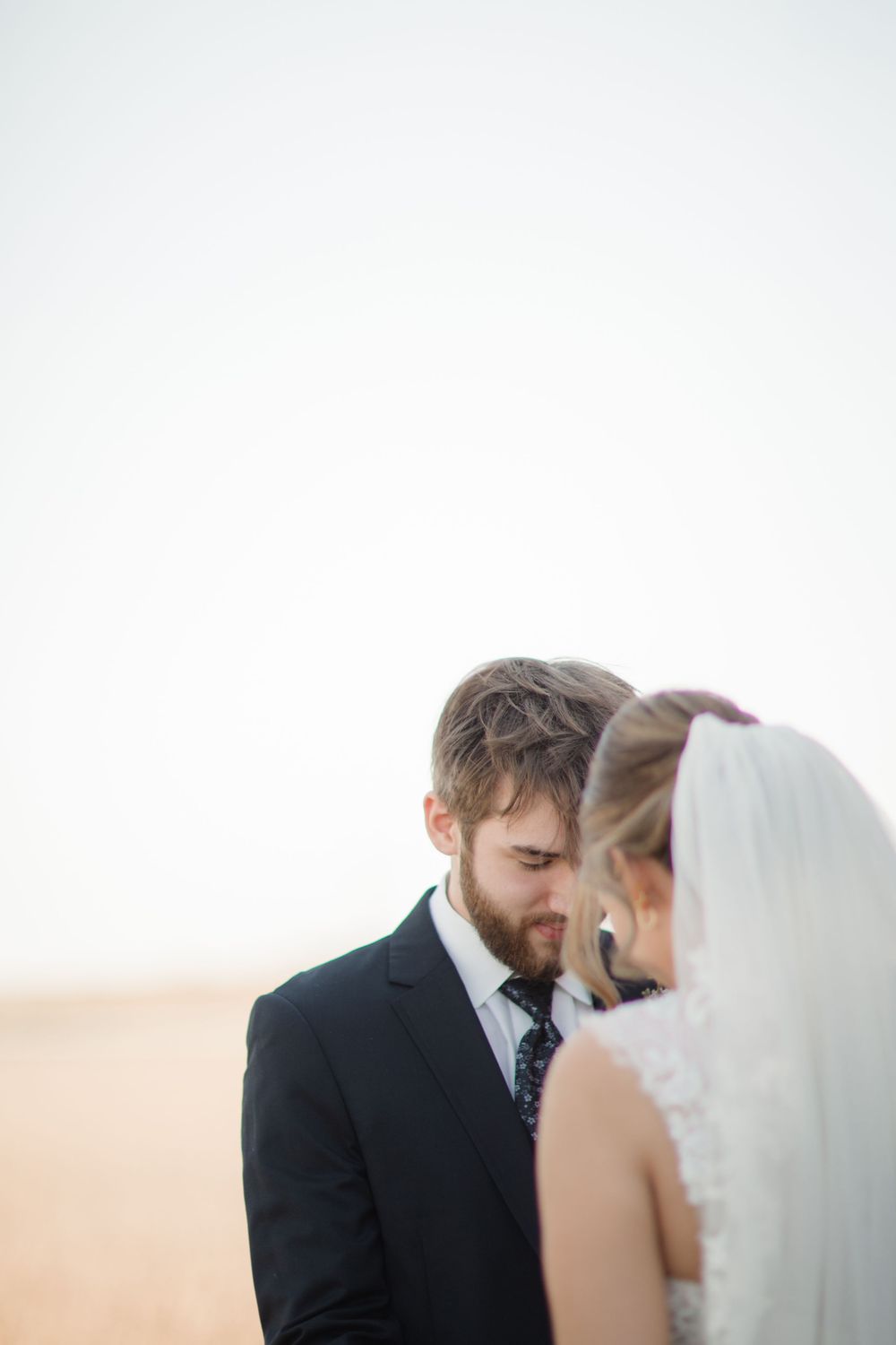 A couple shares an intimate moment during their wedding ceremony with a soft sunset glow in the background.