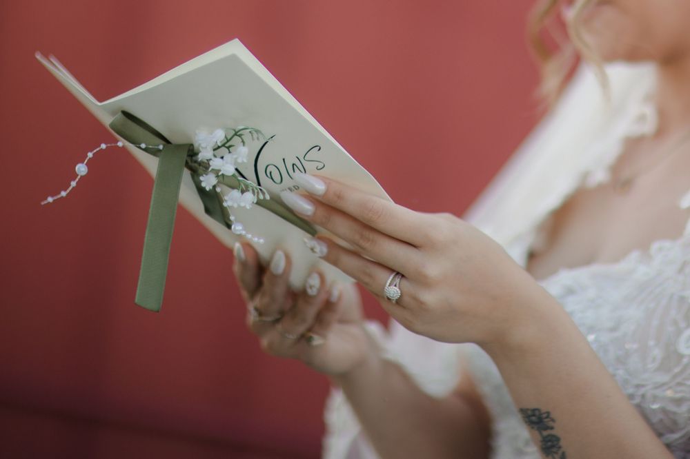 Close-up shots of hands holding and reading handwritten wedding vows on paper against a blurred background.