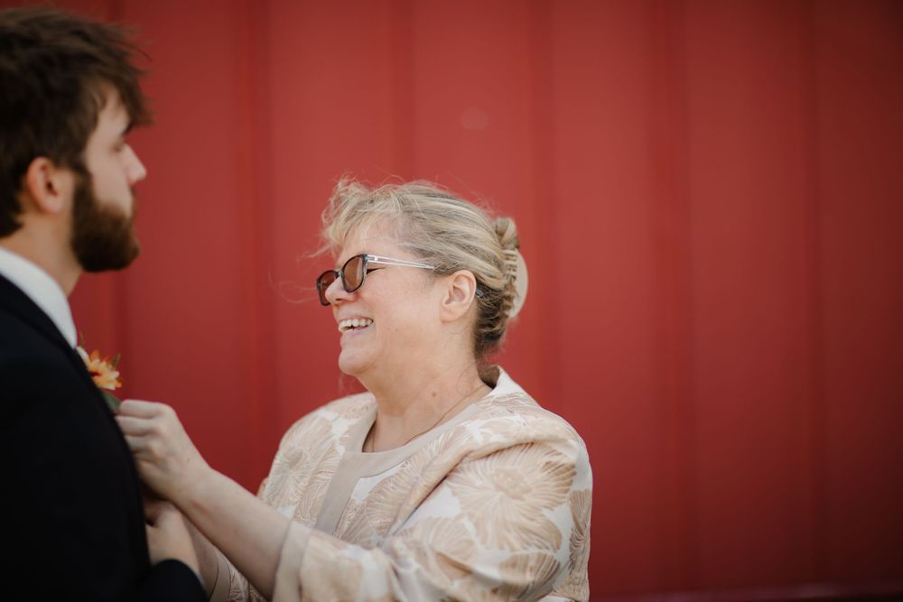 A couple shares a romantic moment during their wedding celebration against a vibrant red backdrop.