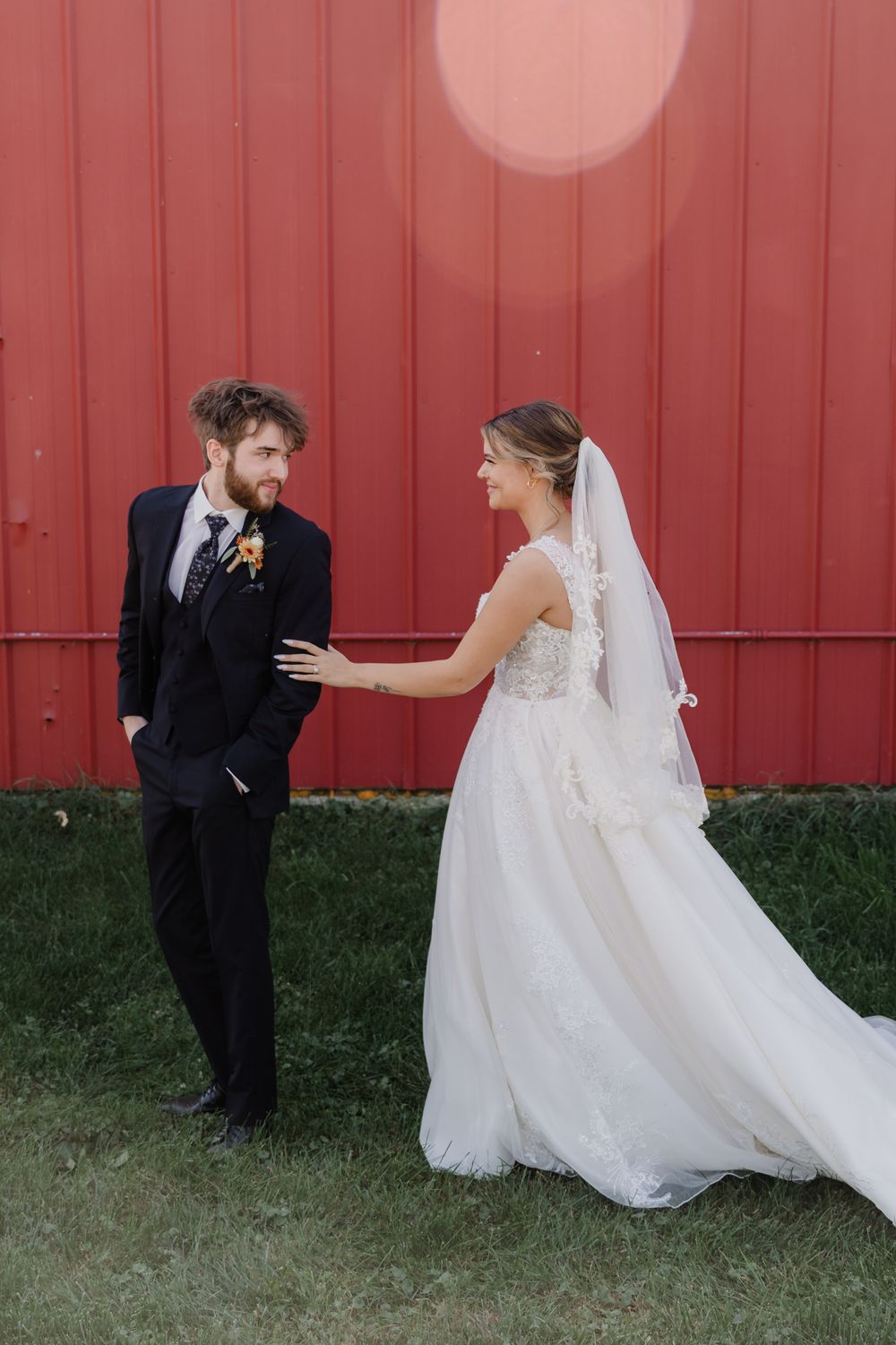 A series of wedding photos showing a couple in formal attire posing playfully against a red barn wall.