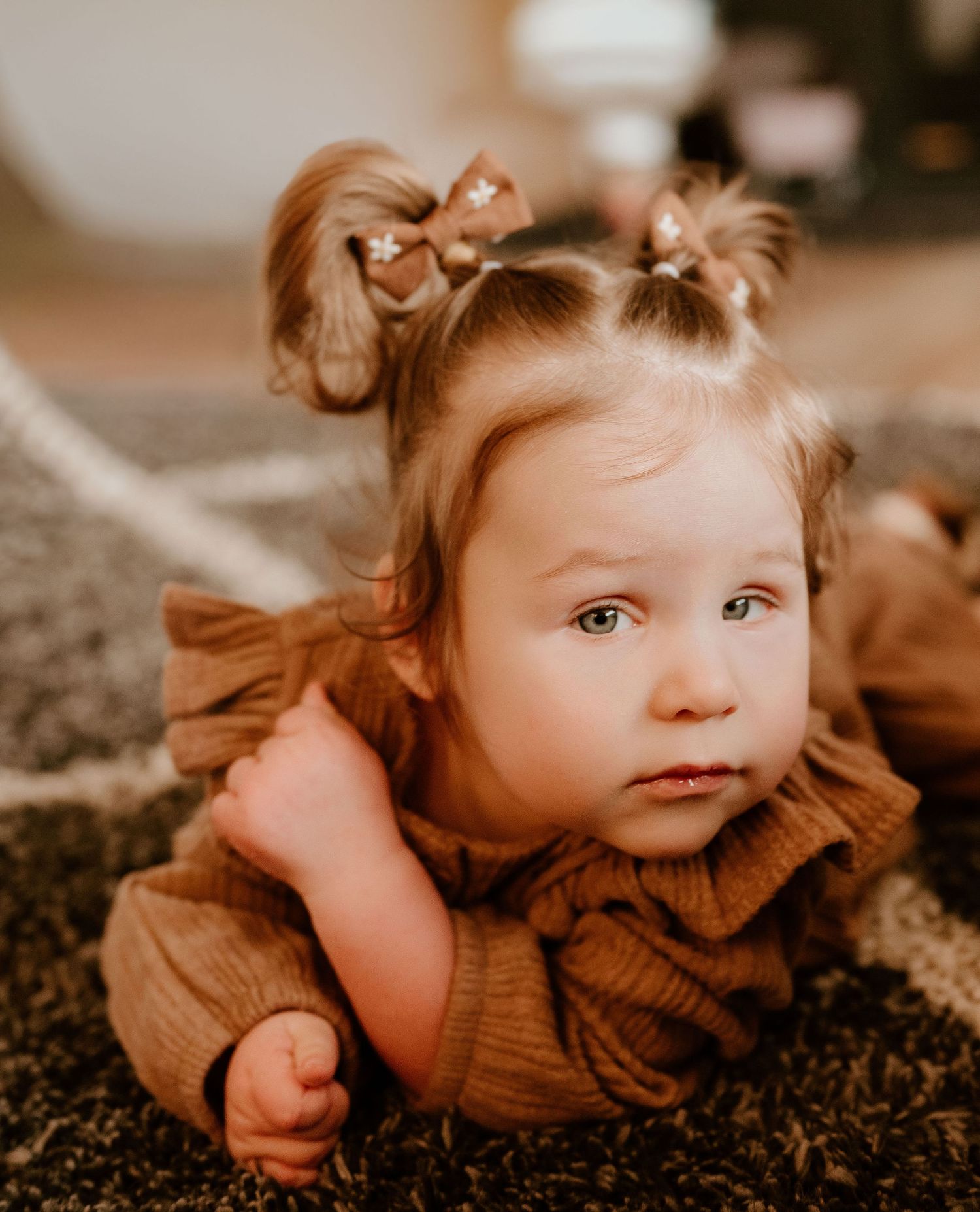 A child in a brown sweater lies on the ground in a sepia-toned artistic portrait series.