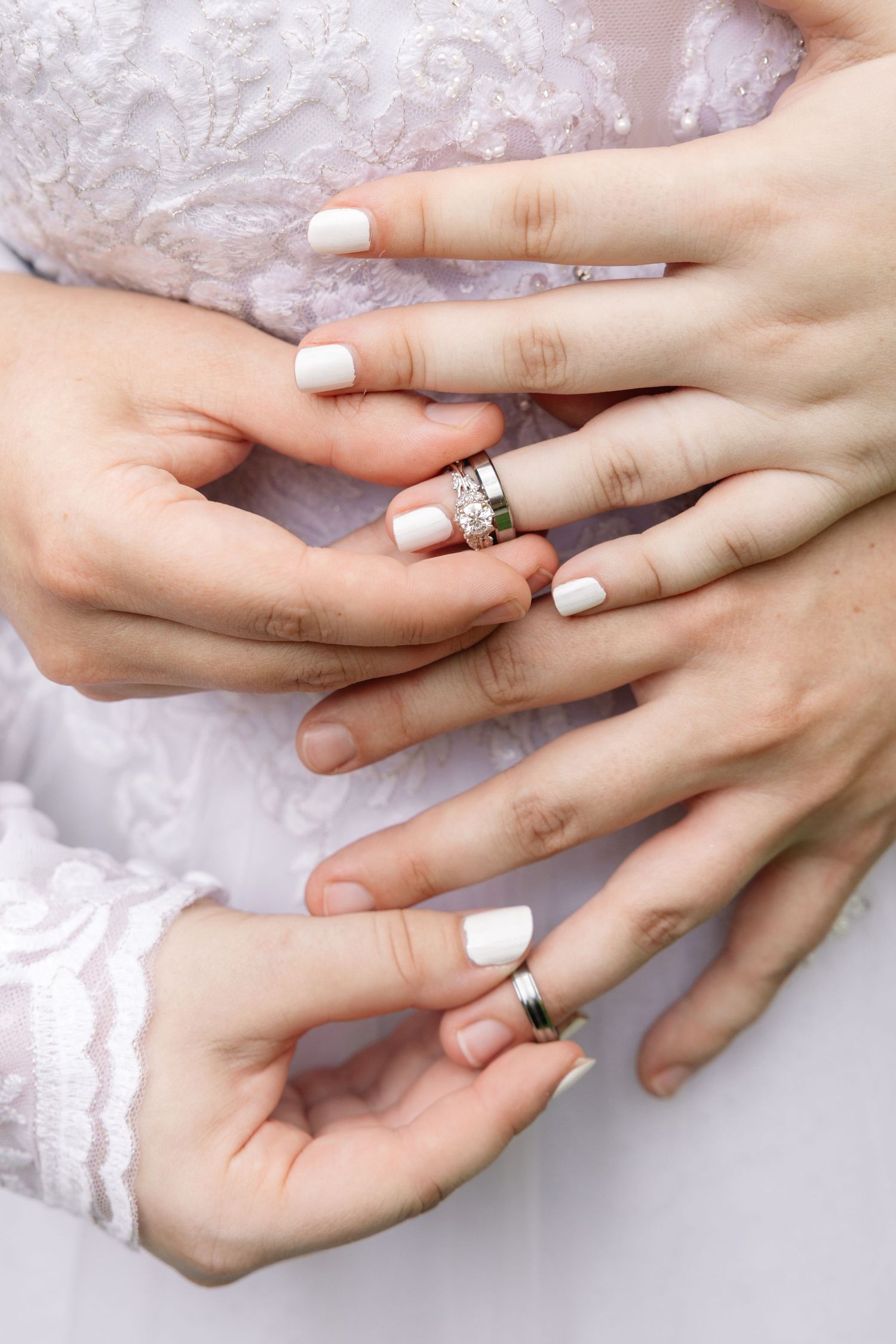 A sequence of close-up photos showing hands exchanging wedding rings during a ceremony on white lace background.