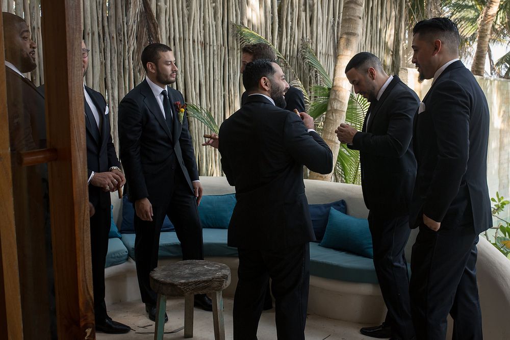 Wedding party members in formal attire socialize in an elegant covered outdoor setting.