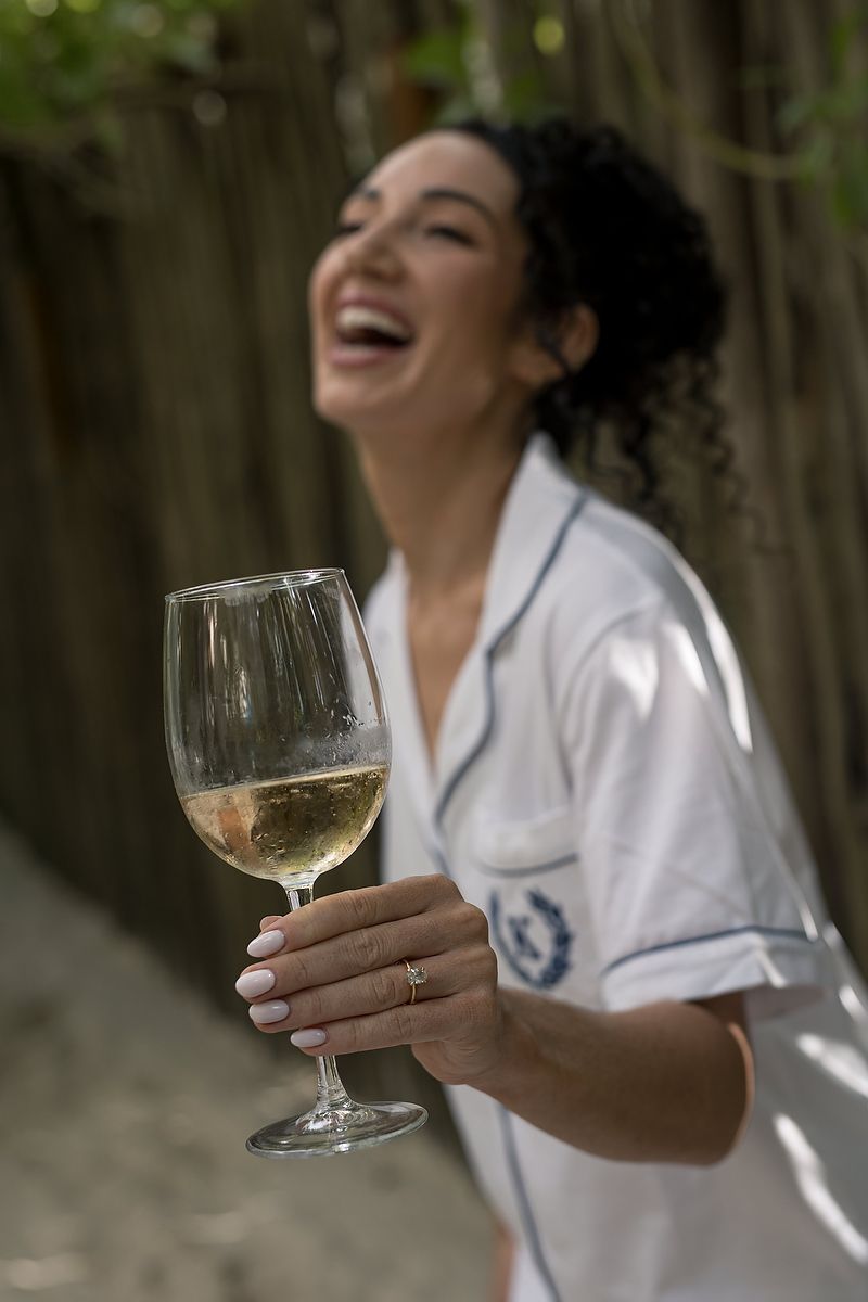 Bride laughing with a glass of champagne during getting ready at Mahayana Tulum; candid fine-art moment from a Tulum beach wedding.