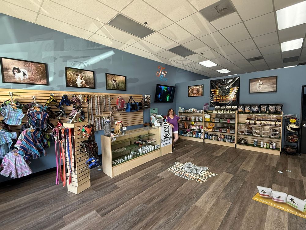 Panoramic view of a retail store interior showing wood flooring, fluorescent lighting, and merchandise displays along the walls.