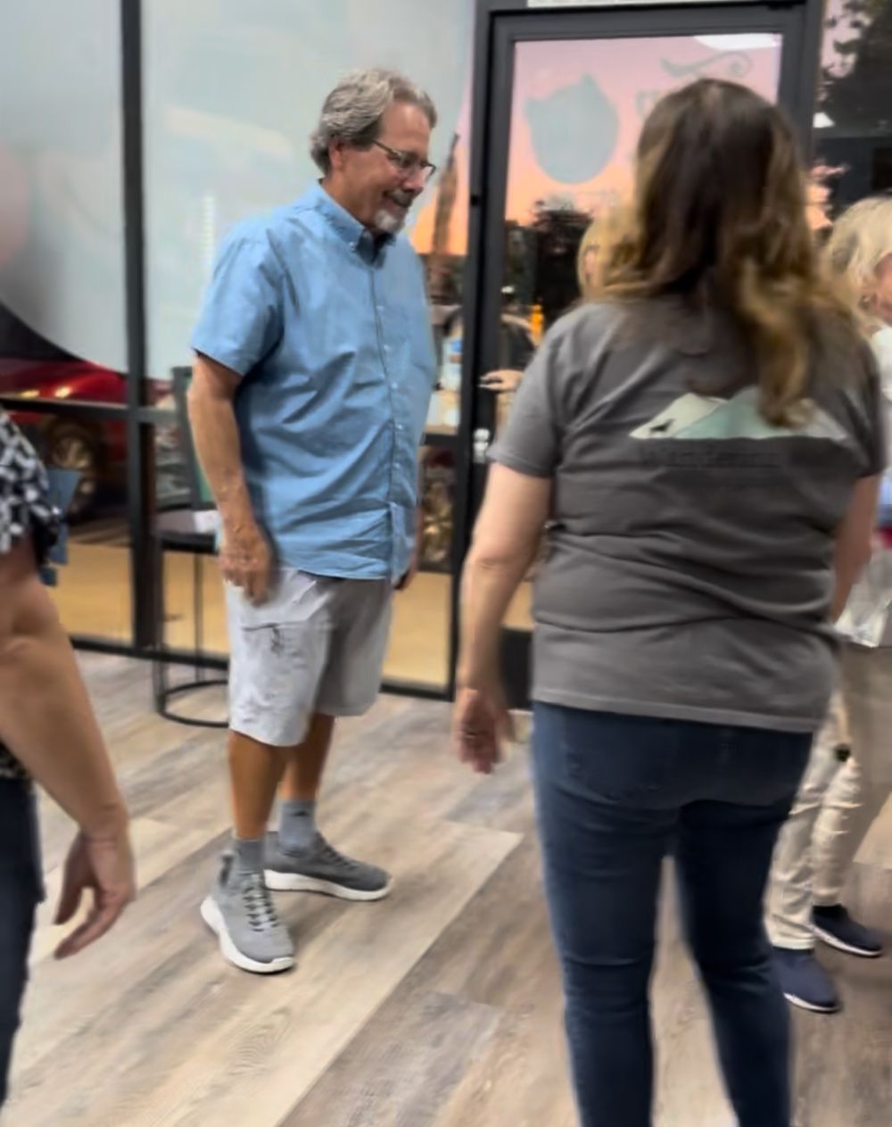 People dancing in a line on a wooden floor during what appears to be a dance class or social gathering.