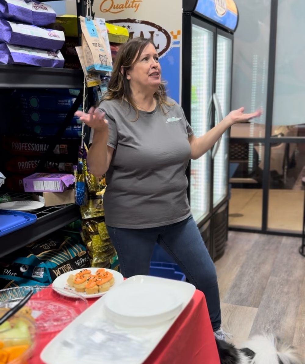 A person in a gray shirt stands in a retail store aisle near shelving units displaying various products.
