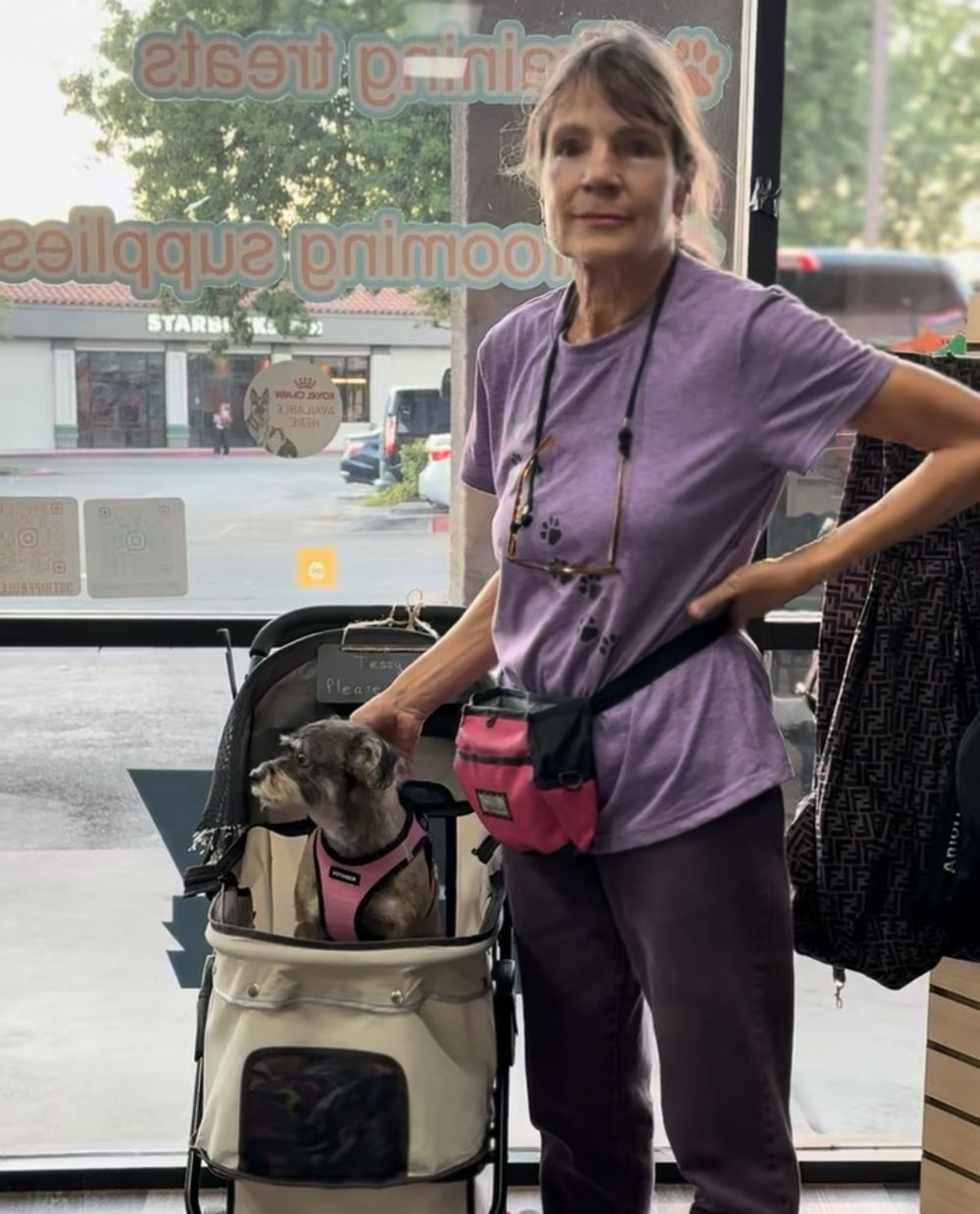 Healthcare worker in purple scrubs assists a small dog being examined on an elevated veterinary table.