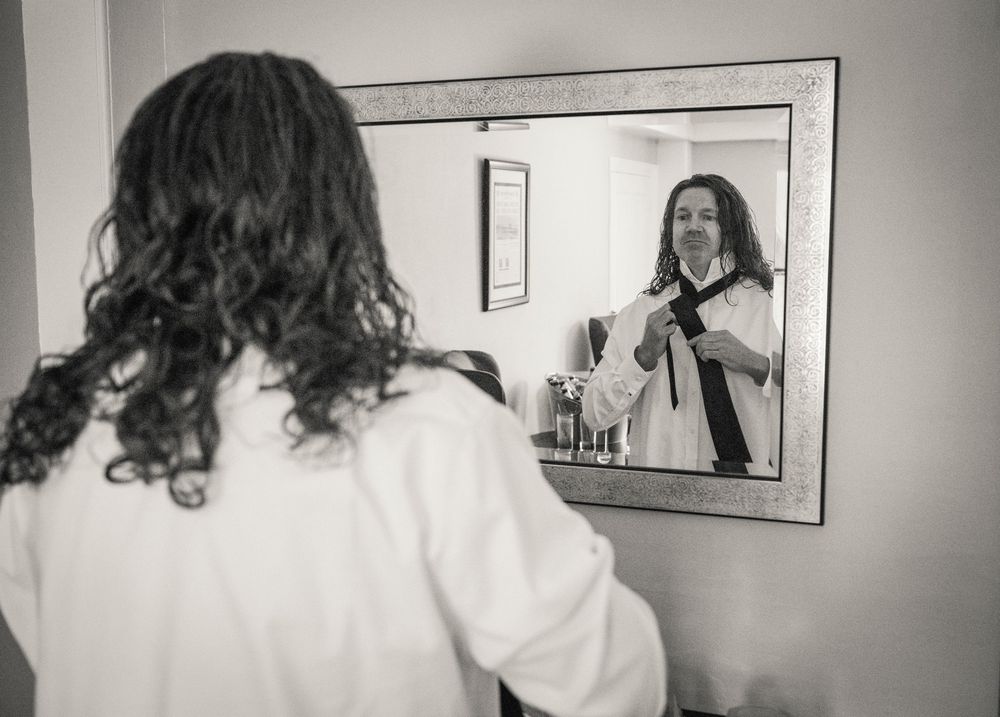 Black and white images of wedding day preparations in a bright room with mirrors.