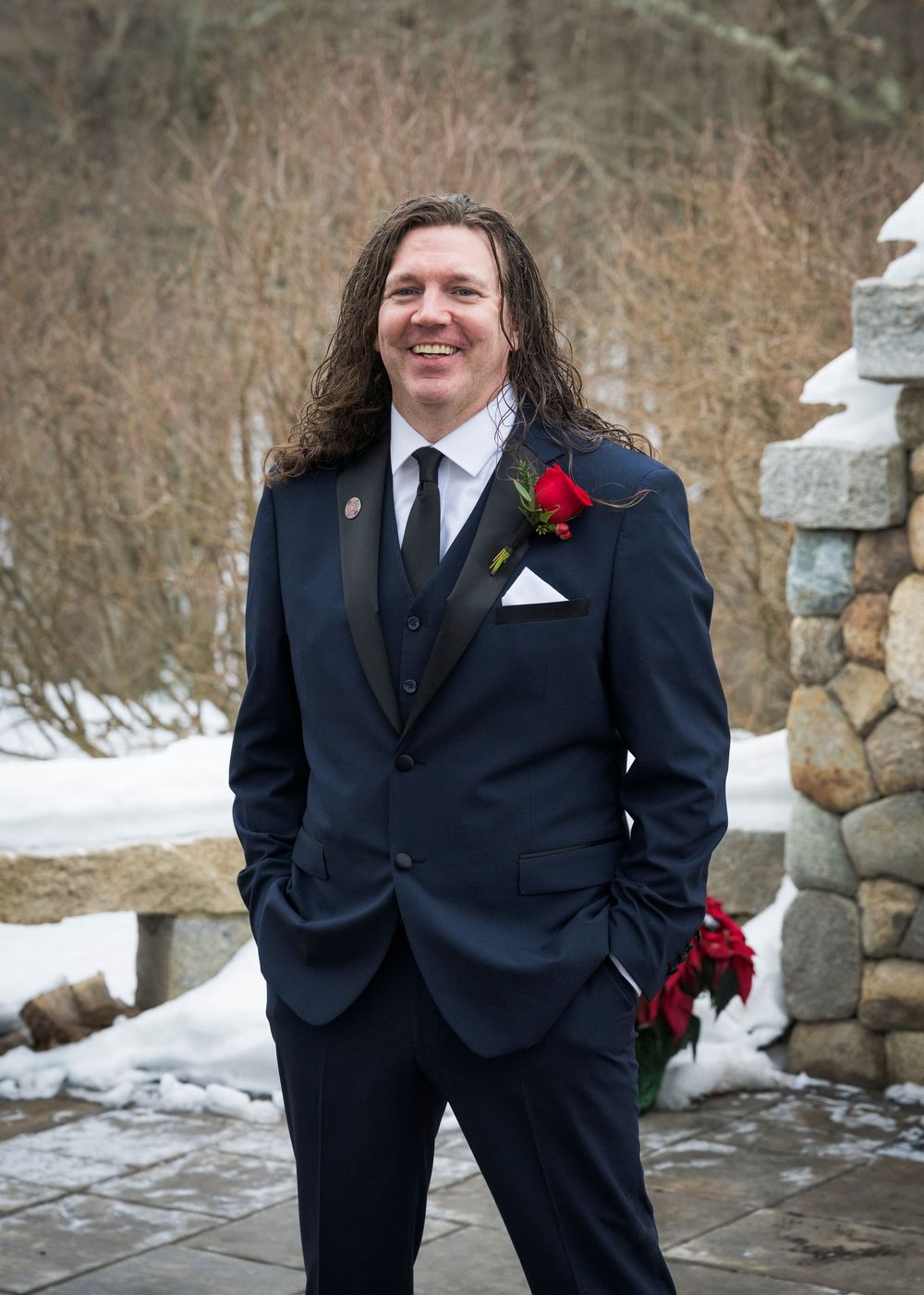 A winter wedding photo session with snow-covered stone walls in the background.