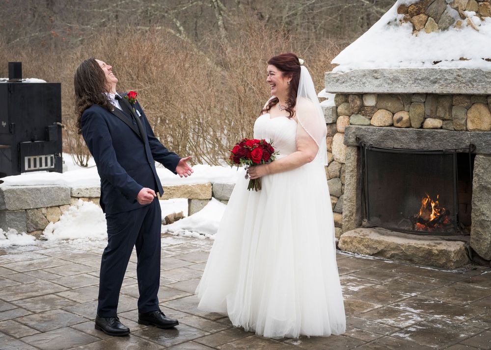 Wedding couple poses on stone patio with snow-covered landscape in background.