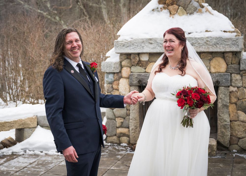 A couple shares romantic moments during their winter wedding photoshoot near a stone wall.
