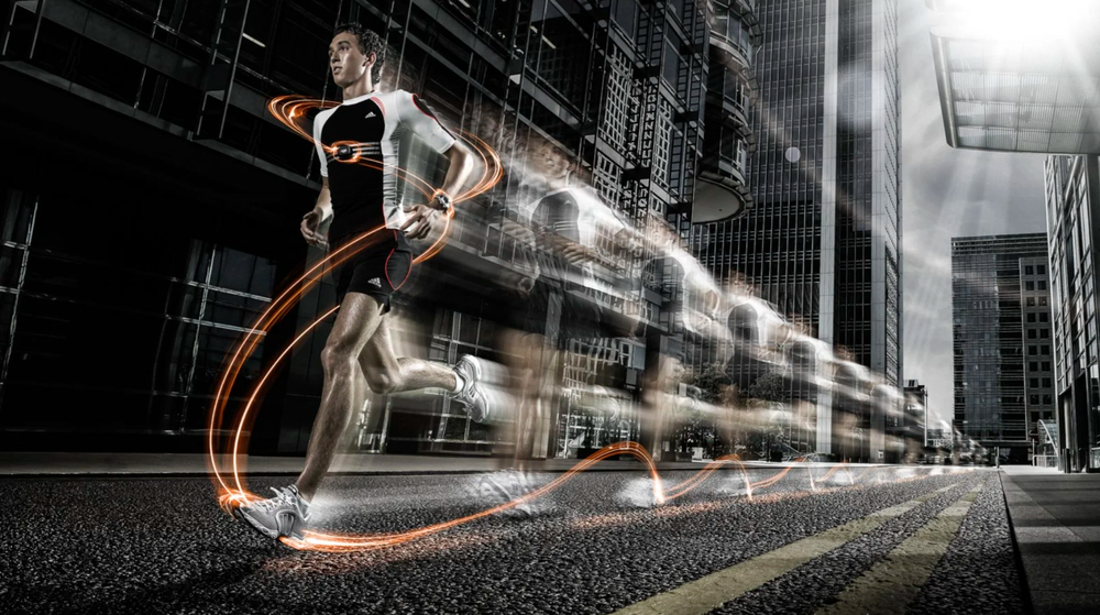 Long exposure photography captures light trails from moving vehicles through a modern urban cityscape at night.