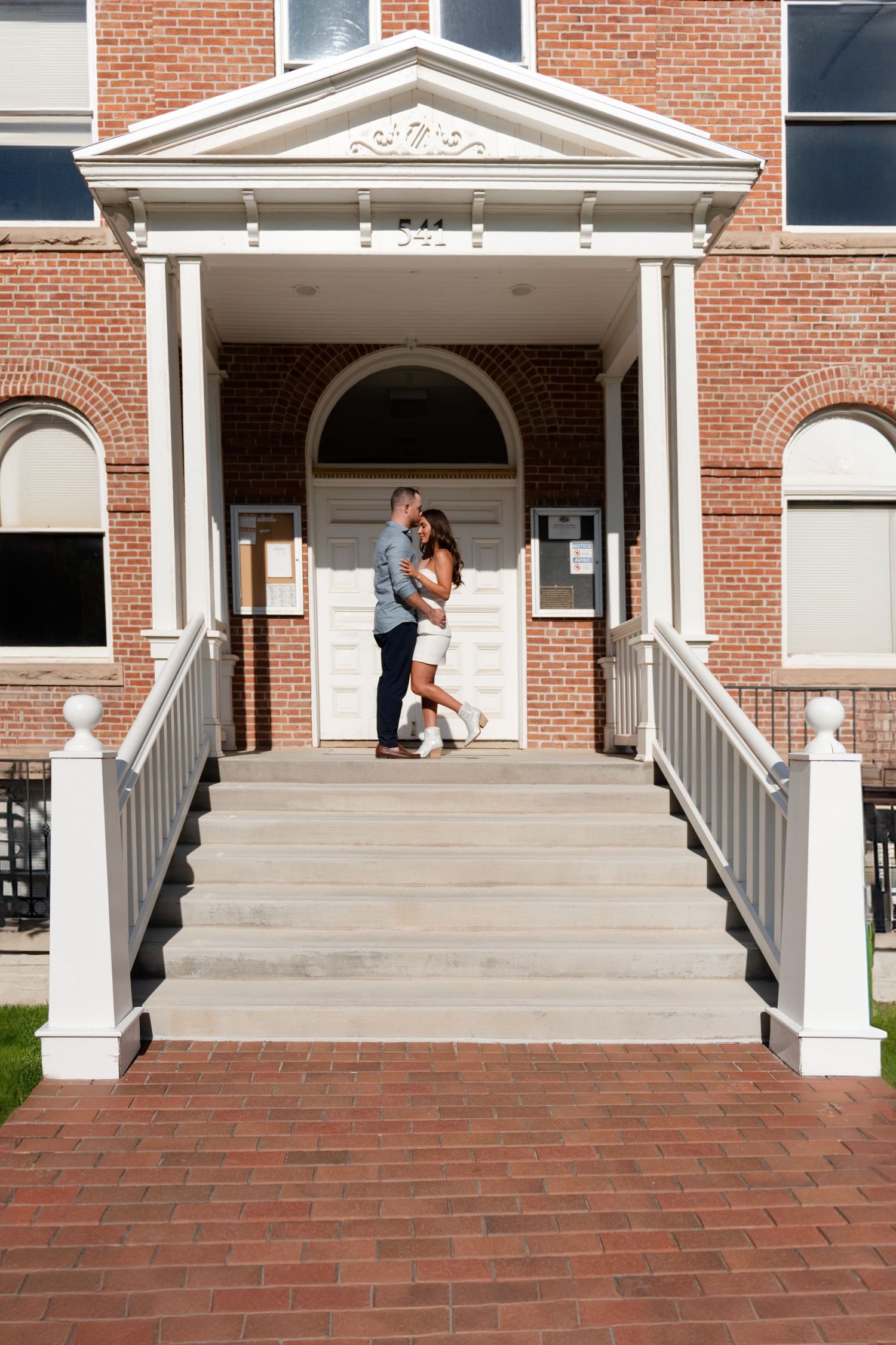 A newly wed couple embracing and kissing on steps of the Ouray county courthouse building with white columns and arched doorway.