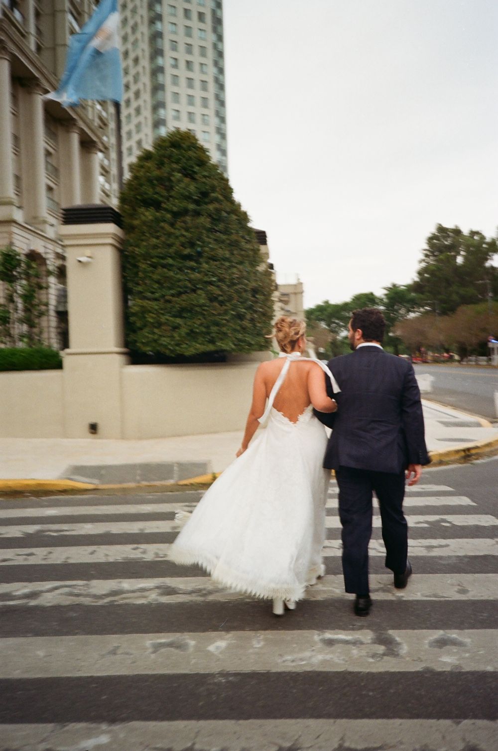 A bride and groom run playfully across a crosswalk in a series of sequential photos showing their movement.