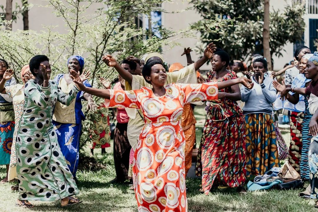 Women dance joyfully in colourful dresses during a community celebration or cultural gathering.