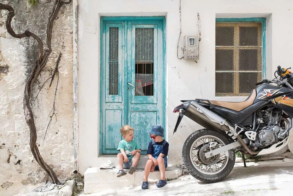 A rustic white wall with turquoise-framed windows and doors creates a charming Mediterranean architectural scene.