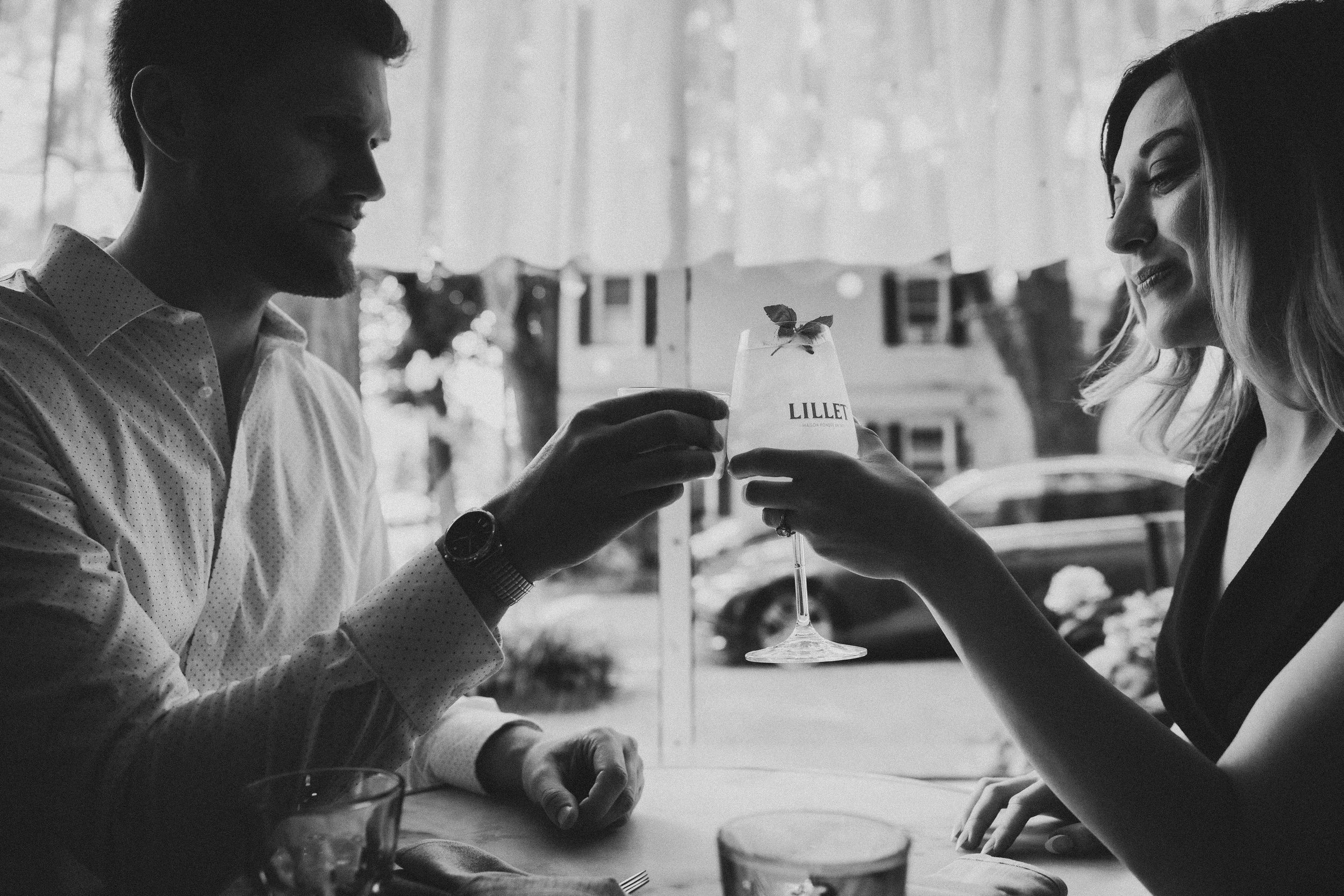 Black and white photo of Hannah and Connor toasting with cocktails inside La Bonne Vache during their intimate Georgetown engagement session