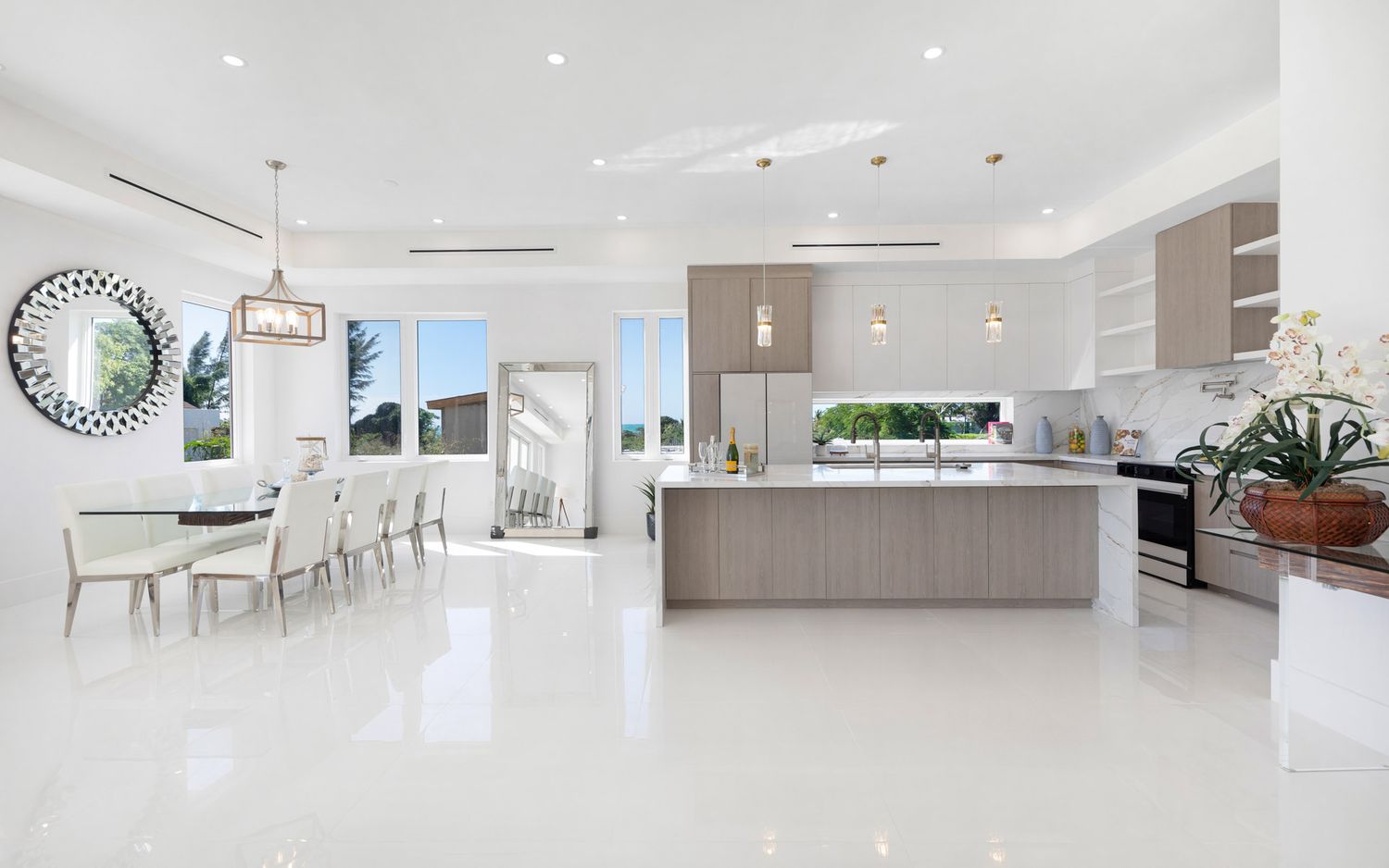 Modern open concept kitchen and living room with white walls, recessed lighting, and hardwood floors.