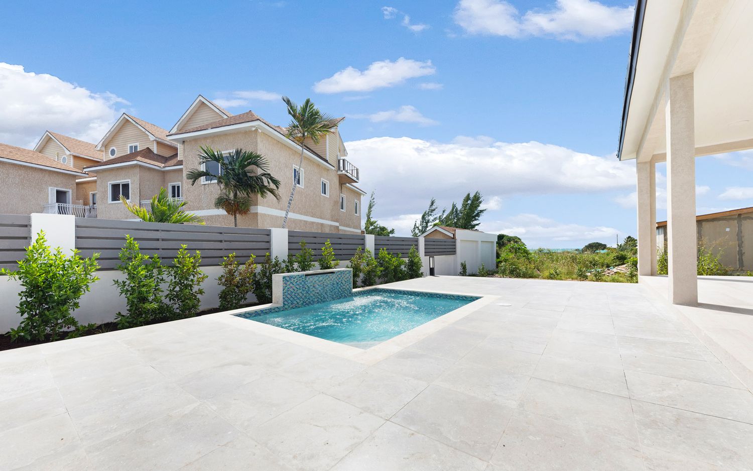 Panoramic view of a modern luxury home exterior with white walls and swimming pool under bright blue sky.