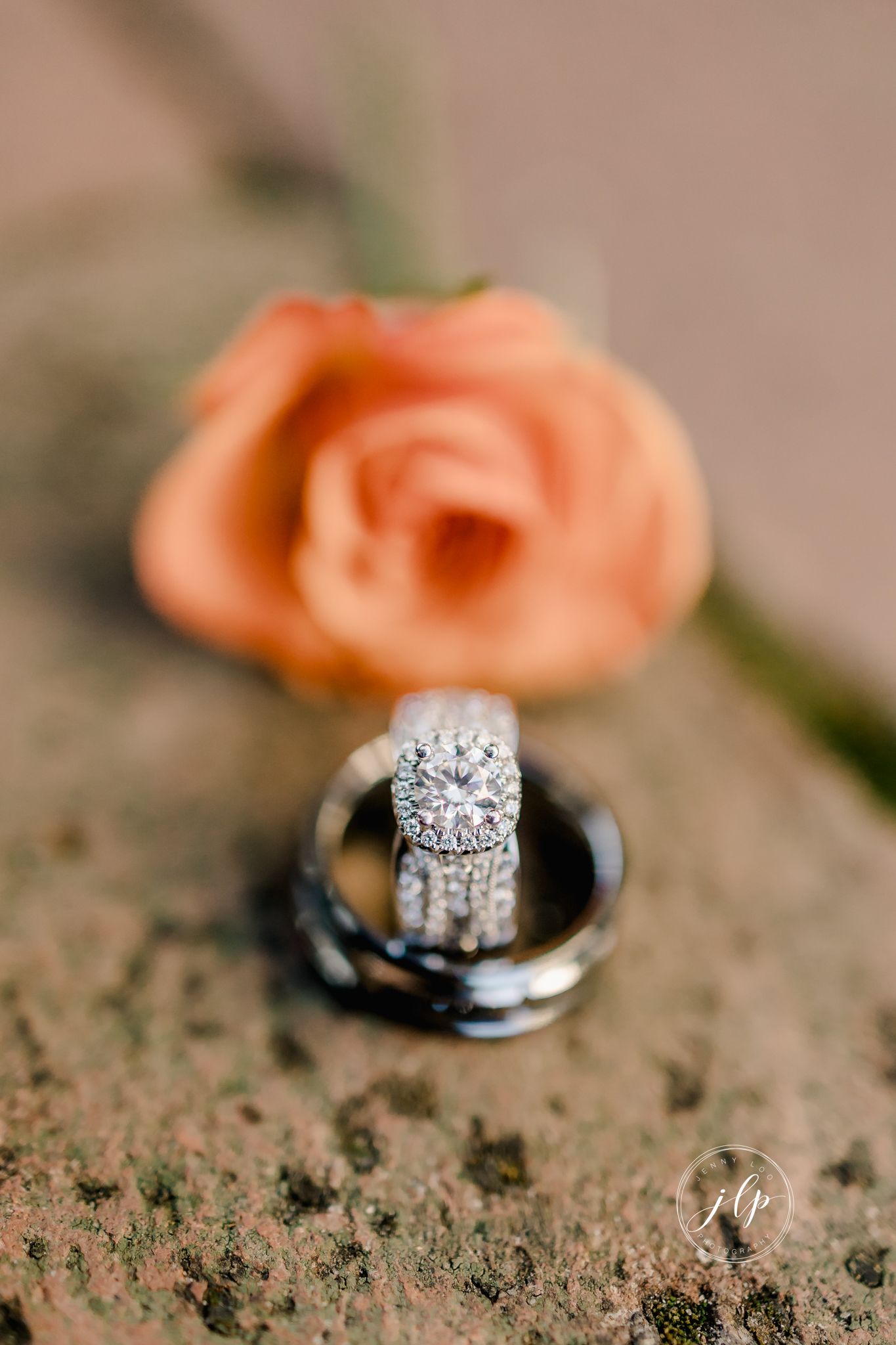 Diamond engagement ring with peach roses in soft focus macro photography.