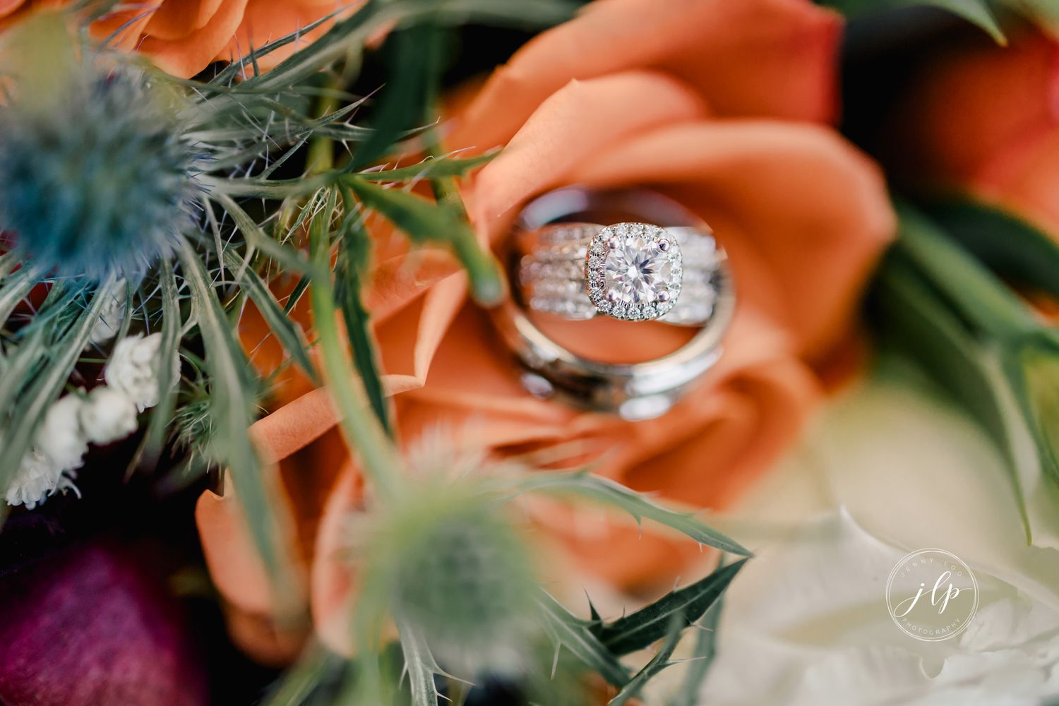 Wedding rings and peach colored flowers arranged artistically in soft focus.