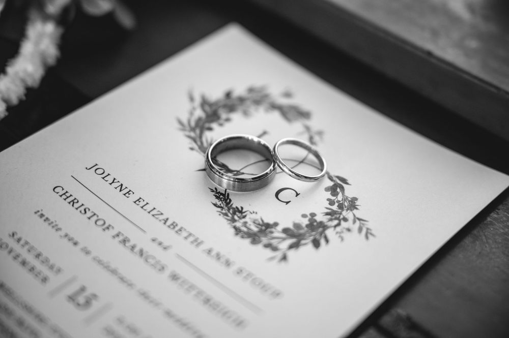 Wedding invitation suite with elegant black and white design showing rings and floral details on paper stationery.