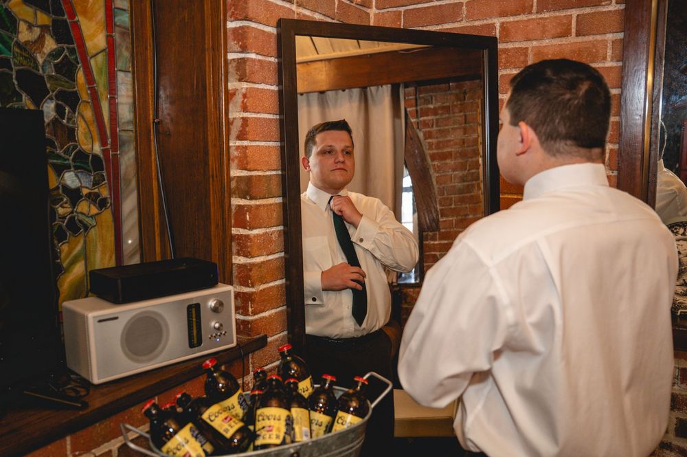 A person in a white shirt stands in a rustic restaurant interior with exposed brick walls and framed artwork.