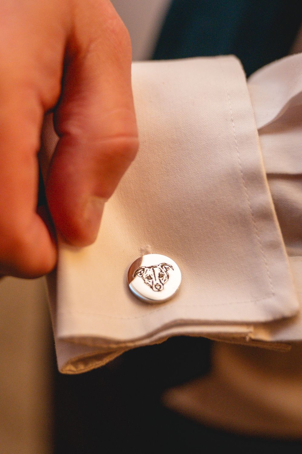 Close-up view of white dress shirt cuffs with decorative cufflinks being adjusted.