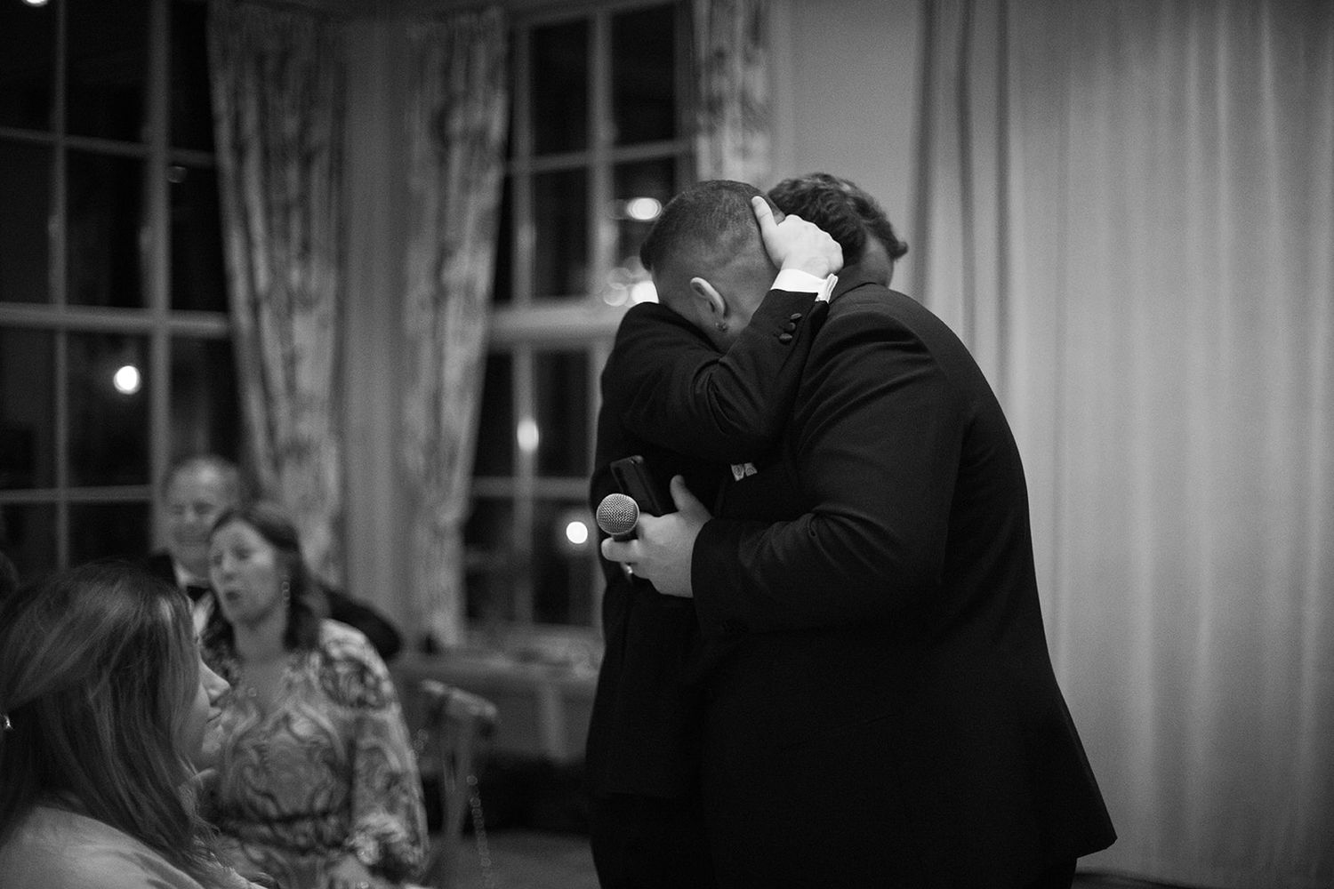 Black and white candid photo of people dancing and celebrating at an elegant indoor reception or party.