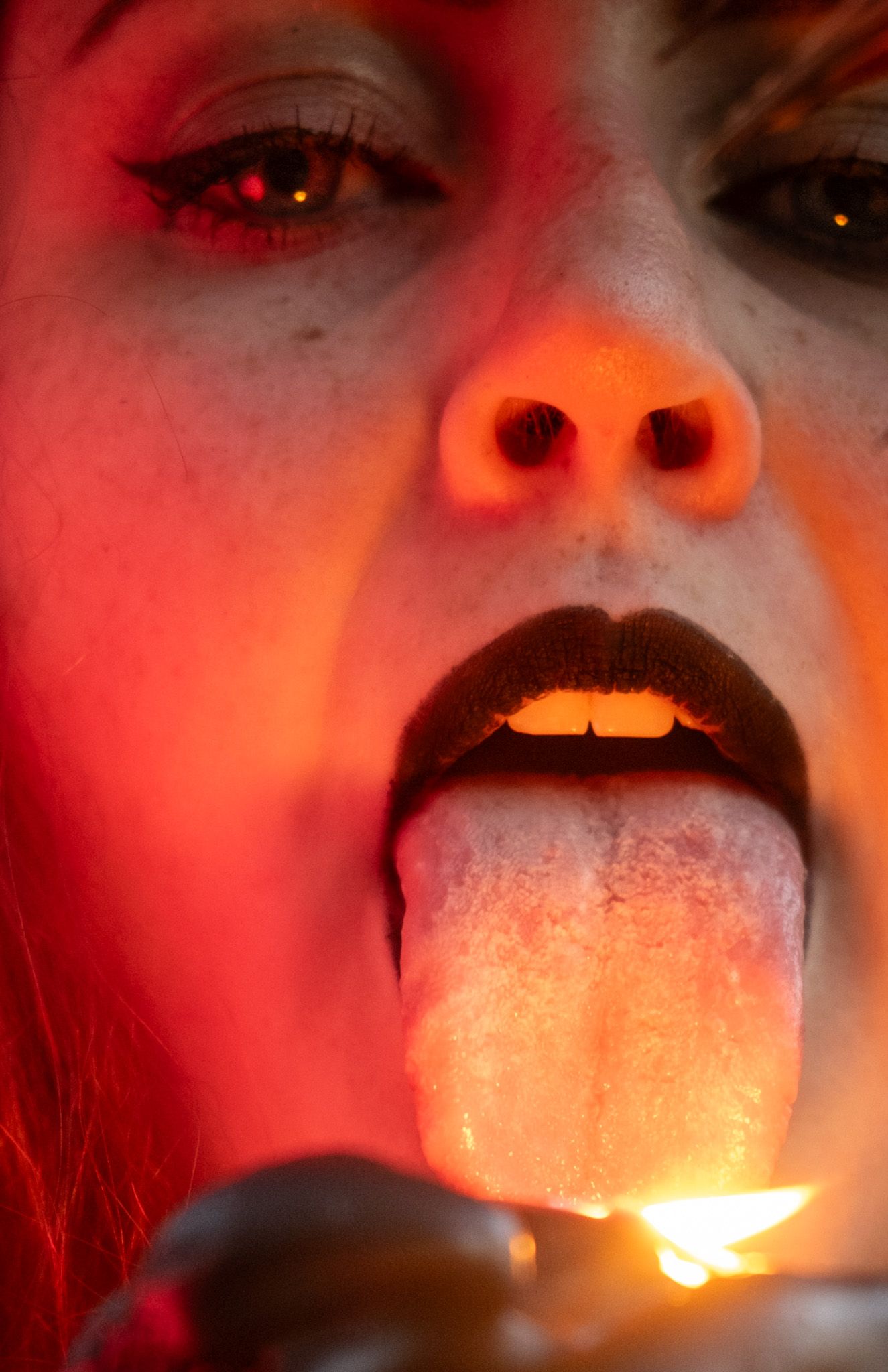 A series of close-up shots show a glowing light stick illuminating someone's mouth in a dark red environment.