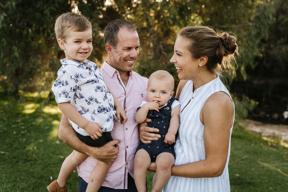 Parents holding their children in golden sunset light at an outdoor family photography session in Perth