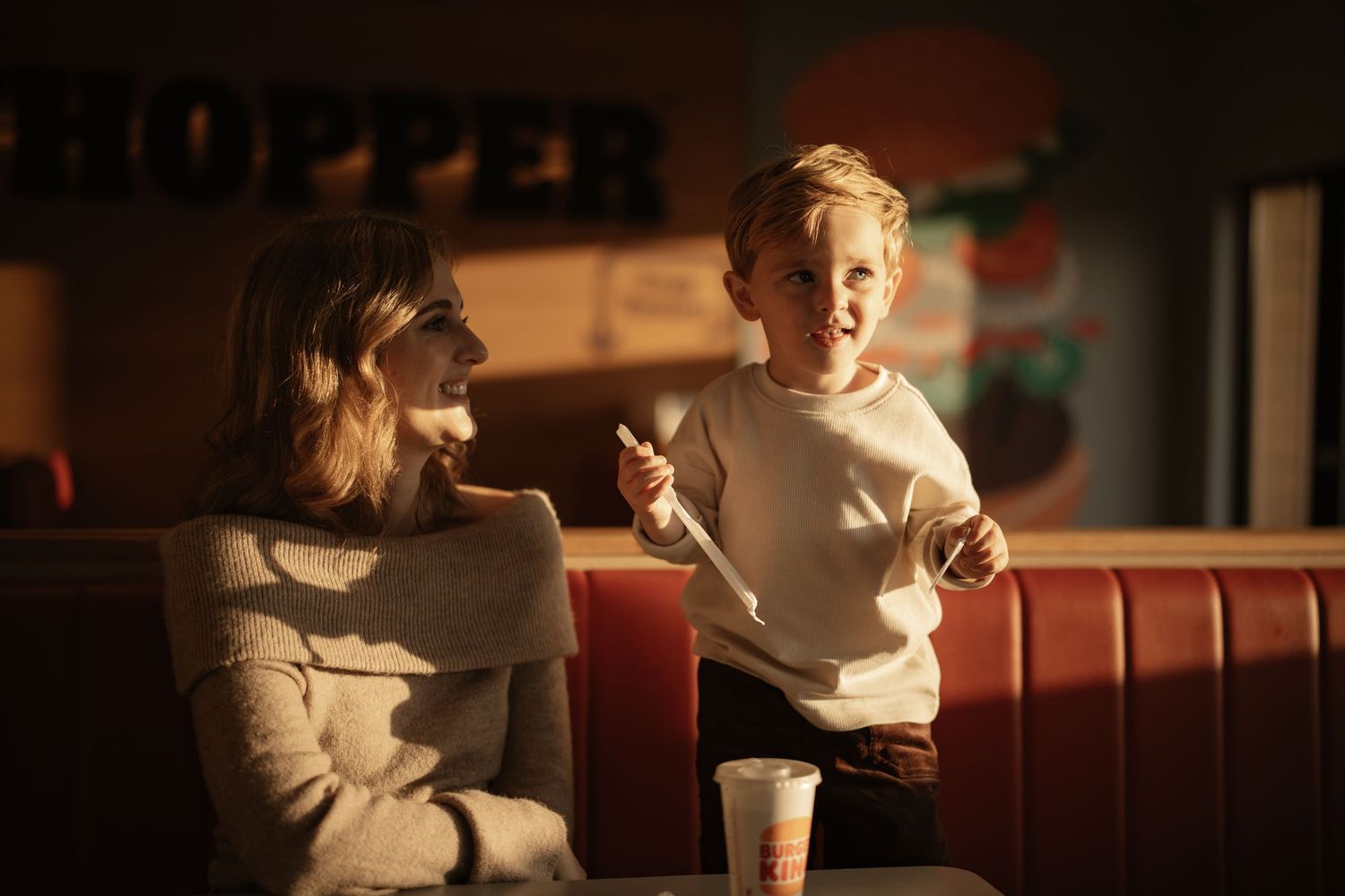 Two people sit together at a diner booth having an animated conversation over coffee.