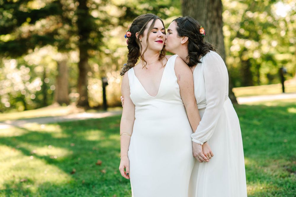 Outdoor wedding ceremony scene in a sunlit park with green grass and trees.
