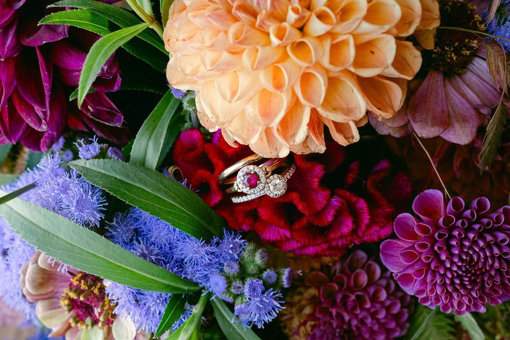 Vibrant floral arrangement featuring peach dahlias, deep burgundy blooms, and purple limonium with green foliage.